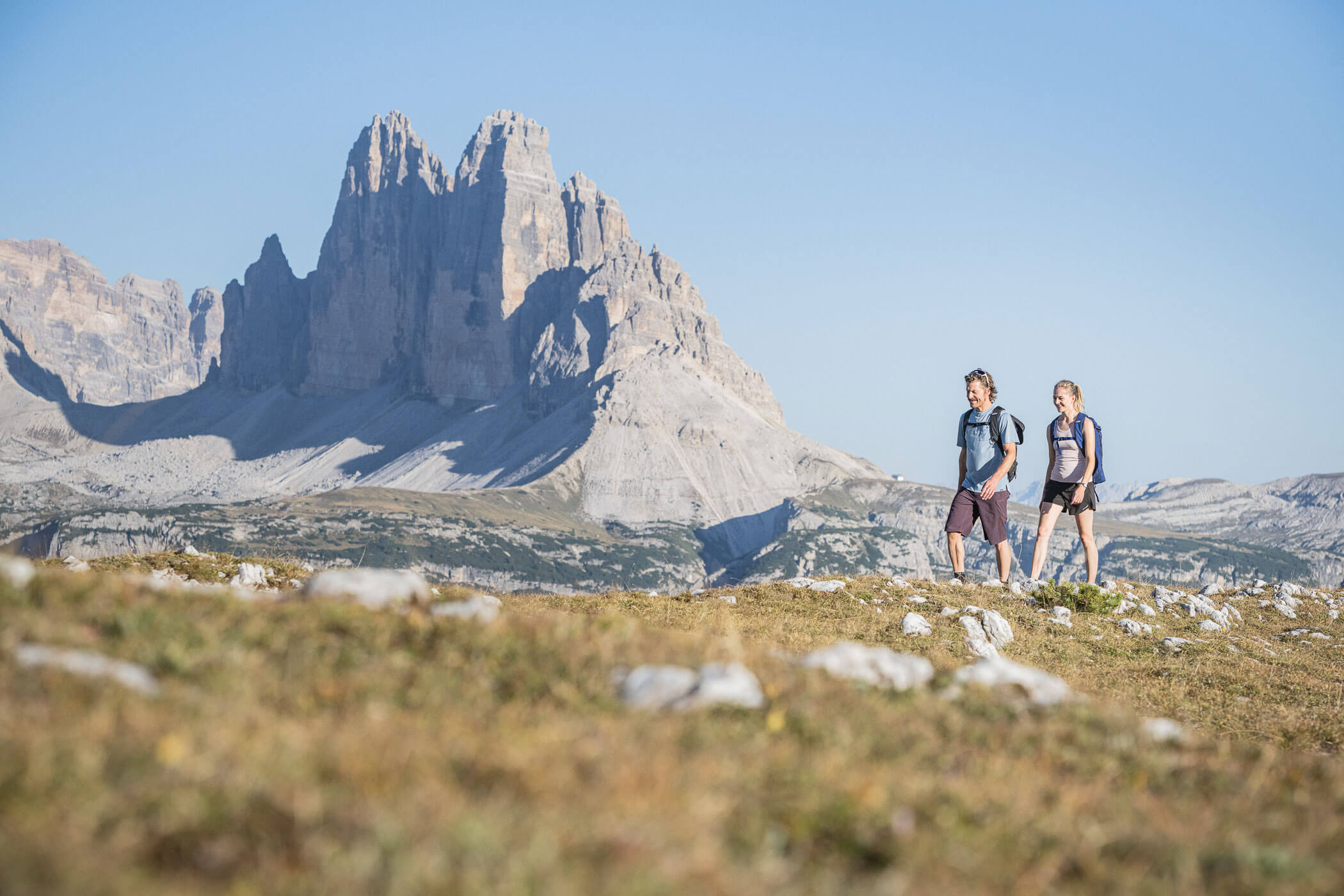 Zwei Personen wandern vor den Drei Zinnen in Sexten - Kuenzerhof
